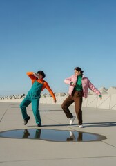 Fototapeta premium Two Young Women in Colorful Retro Outfits Dancing Outdoors on a Sunny