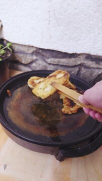 Person POV removing fried dough from hot oil