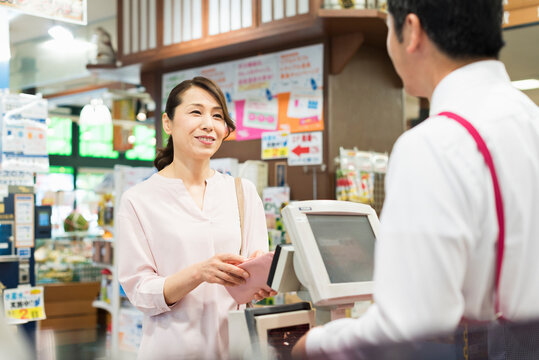スーパーマーケットのレジで買い物をする40代女性