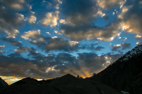 View of Goro II campsite at sunset with dramatic clouds over the Karakoram mountain range in Gilgit, Pakistan.