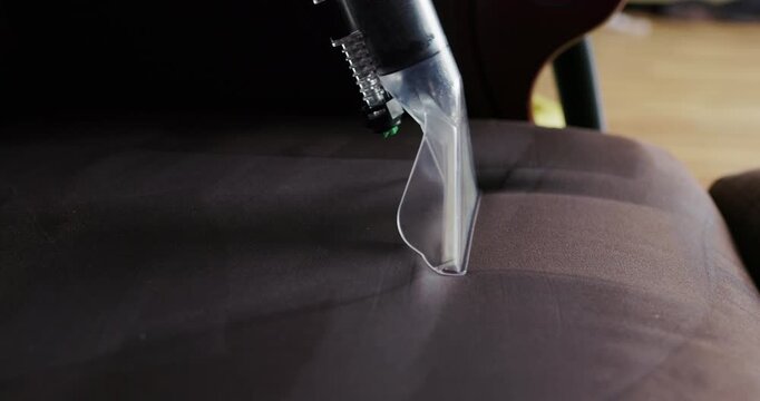 Close up of washing vacuum cleaner nozzle cleaning dark sofa