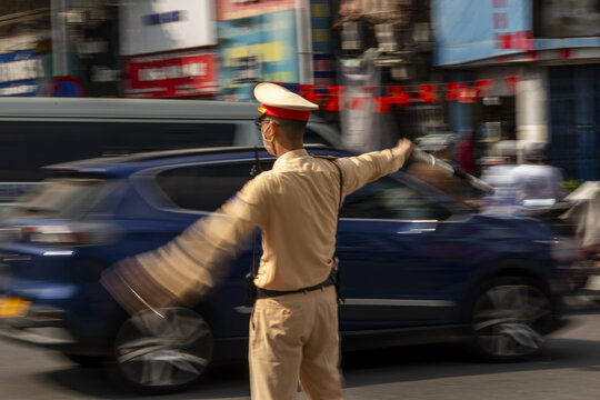 View of a traffic police officer in uniform directing vehicles on a busy street in Hanoi, Ha Noi, Vietnam.