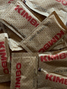 Mallorca, spain, june 20, 2026 kimbo branded brown sugar packets, also known as zucchero di canna, showing a texture of coffee beans