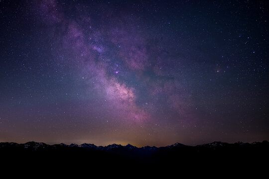 View of the Milky Way galaxy stretching across the night sky above the dark silhouette of the Olympic Mountains at Hurricane Ridge, Clallam County, Washington, United States.