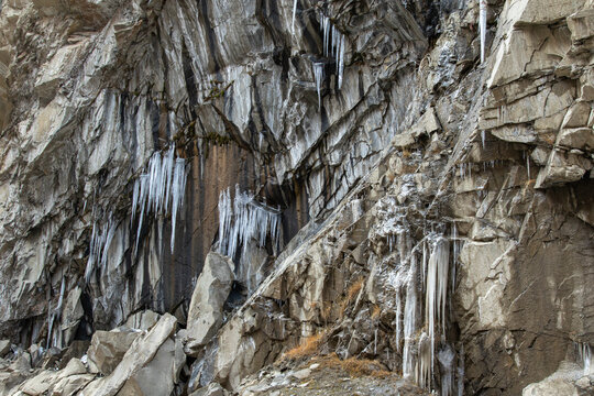 View of the rugged rock face of Khunjerab Pass featuring sharp stone textures and hanging icicles in the cold mountain landscape of Hunza Nagar, Gilgit, Pakistan.