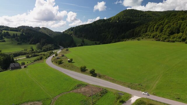 Drone Shot of a White Car Driving Along a Mountain Road near Cicmany, Slovakia