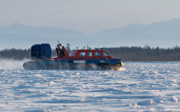 View of a hovercraft gliding over the frozen surface of Lake Baikal with snow-covered mountains in the background in Severobaykalsk, Buryatia, Russia.