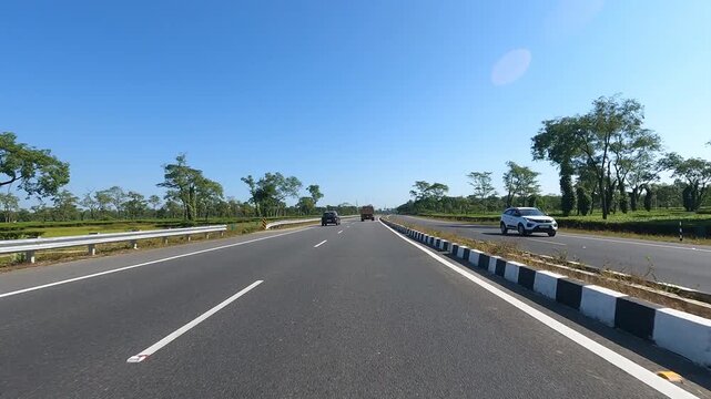 A beautiful high-speed shot along the National Highway captures rows of shady trees lining the roadside, revealing a mesmerizing scene where nature and motion blend in graceful harmony. 4K