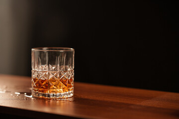 Whiskey Glass on Wooden Counter in Dim Lighting © aekachai