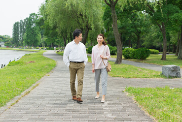 Obraz premium 湖畔の並木道を散歩する40代夫婦