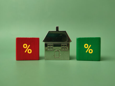 A silver model house sits positioned between a red block and a green block, both displaying yellow percentage symbols