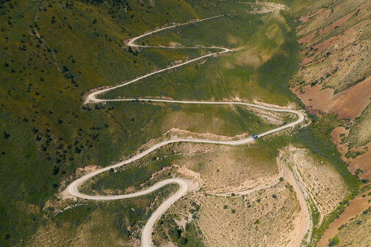 Aerial view of the winding switchbacks of 33 Parrots Pass with a car driving on the serpentine mountain road in Jety - Oguz, Issyk-Kul Region, Kyrgyzstan.