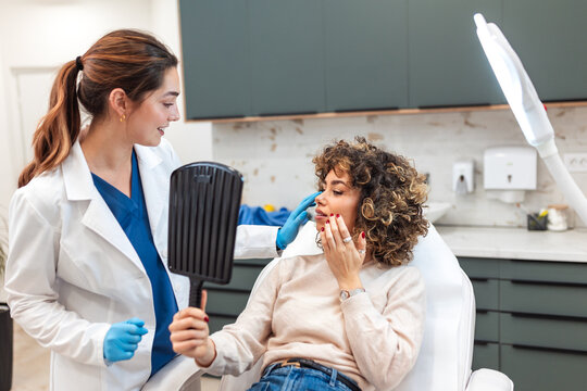 Patient looking in a mirror after a cosmetic procedure, doctor checking results. Aesthetic clinic, beauty treatment, facial enhancement, healthcare, wellness, medicine, patient experience, care.