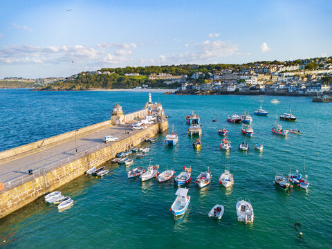 Aerial view of fishing boats moored in the turquoise waters of St Ives Harbour next to Smeaton's Pier and the coastal town in St Ives, England, United Kingdom.