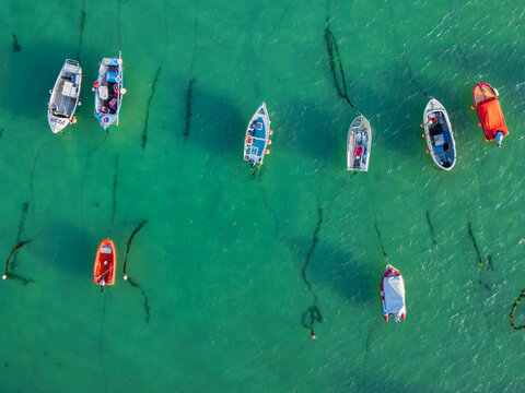 Aerial view of small fishing boats and pleasure craft anchored in the clear turquoise waters of St Ives Harbour, St Ives, England, United Kingdom.