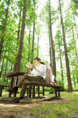 Fototapeta premium 公園のベンチで読書を楽しむ40代夫婦
