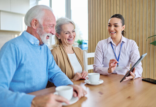 Senior couple having a meeting with an agent, businesswoman, salesperson or doctor using a tablet computer  in his office