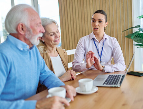 Senior couple having a meeting with an agent, businesswoman, salesperson or doctor using a laptop computer  in his office