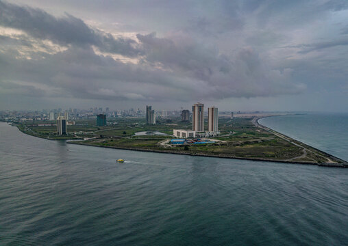 Aerial view of the modern skyscrapers of Eko Atlantic City and the coastline of Tarkwa Bay Beach under a cloudy sky in Lagos, Lagos, Nigeria.