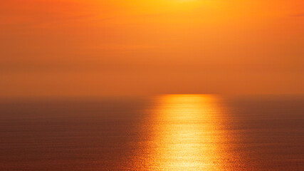 Fototapeta premium The beautiful golden sunset over the calm ocean horizon with sun reflection on water surface background