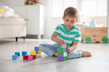 Little boy playing with colorful blocks on floor at home © New Africa
