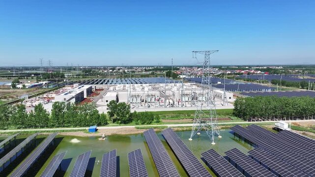 Aerial view of a large-scale photovoltaic power station and substation complex under clear blue sky