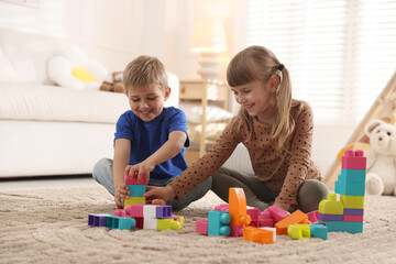 Naklejka premium Little kids playing with colorful blocks on floor at home