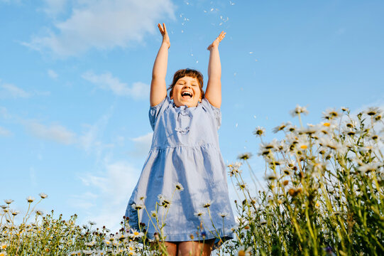 Happy young girl throwing flower petals into the air