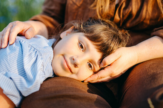 Young girl resting with her mother in meadow