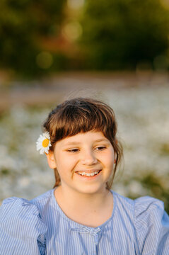 Smiling child girl with daisy flower behind her ear