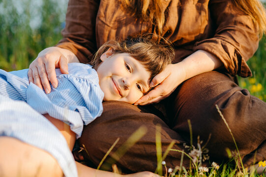 Child girl resting on mother's lap outdoors