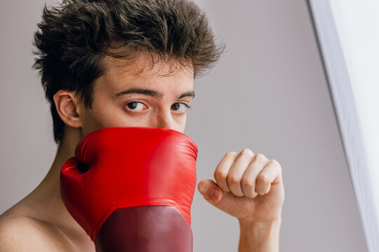 Young man with red boxing glove looks intensely