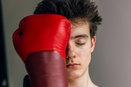 Teenager boy with eyes closed on red boxing glove