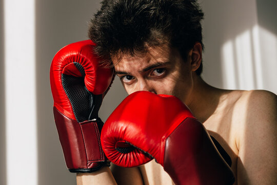 Young man with red boxing gloves stares intensely