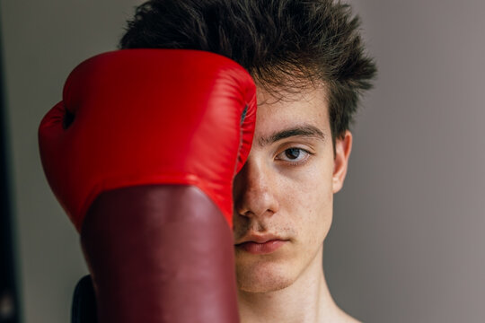 Young man covers his eye with a red boxing glove