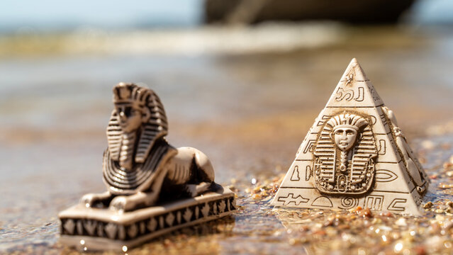 Ancient lion statue rests beside pyramid model