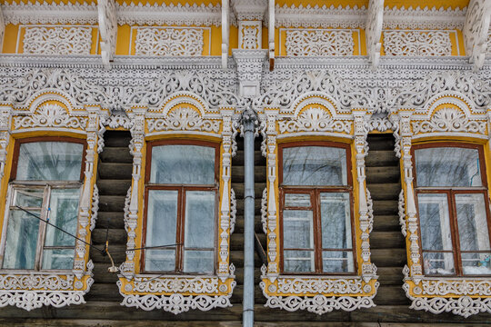View of traditional Russian wooden house with intricate white carved window frames and yellow trim in Tomsk, Tomsk Oblast, Russia.