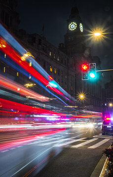 View of The Bund at night featuring long exposure light trails from traffic, historic architecture, and a glowing clock tower in Shanghai, Shanghai, China.