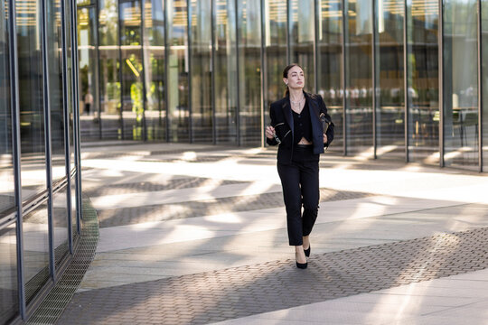 Businesswoman walks confidently through modern office building at midday in a city center