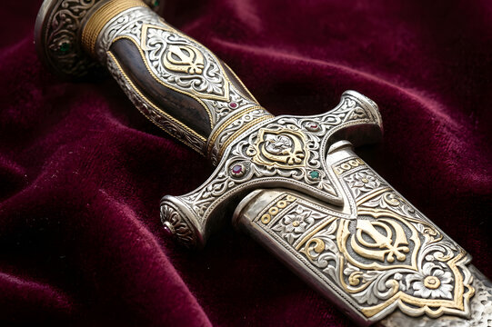 Close up of ornate ceremonial kirpan dagger handle on maroon velvet