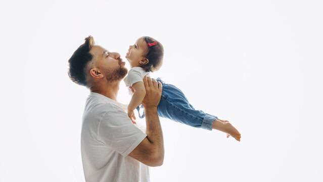  Father taking daughter in his arms in photo studio. Happy Father's Day together.