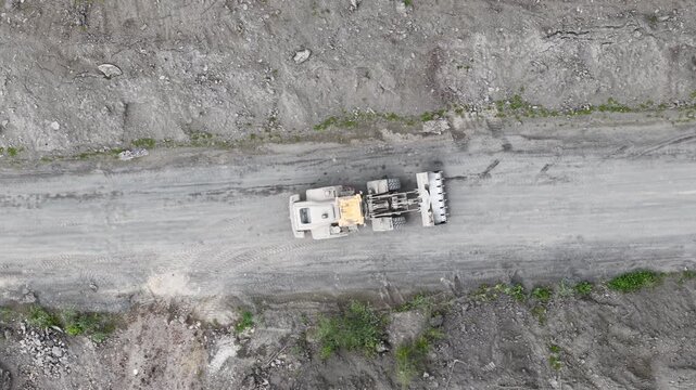 A heavy bulldozer operates on a dirt road within a construction site, viewed from directly above.