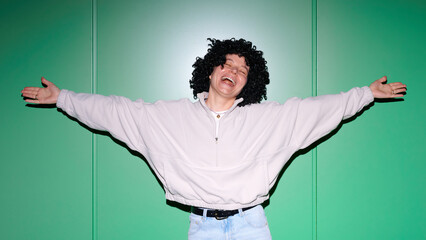 Naklejka premium Joyful young woman with curly wig and arms outstretched in a gesture of pure happiness and freedom