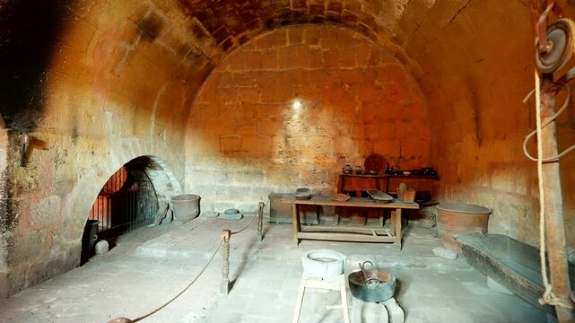 Handheld footage of a historic stone kitchen interior with arched walls, traditional cookware and rustic tools inside Santa Catalina Monastery in Arequipa, Peru