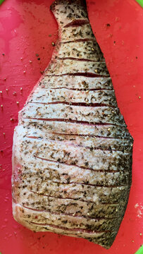 Fresh cleaned carp cut into pieces and seasoned with spices on a wooden board before baking. Preparing homemade fish dishes. Healthy protein-rich food and traditional cooking concept.