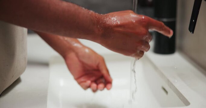 Basin, washing hands and water with person in bathroom for grooming, hygiene or skincare routine. Cleaning, health and wellness with man at sink in home to remove bacteria or germs for disinfection