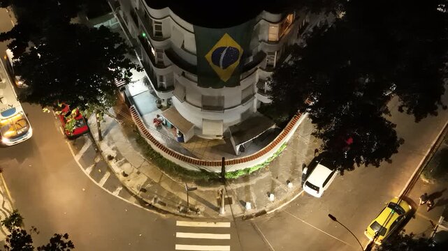 Aerial view of a street corner at night with a large Brazilian flag hanging on a building in Rio de Janeiro, State of Rio de Janeiro, Brazil.