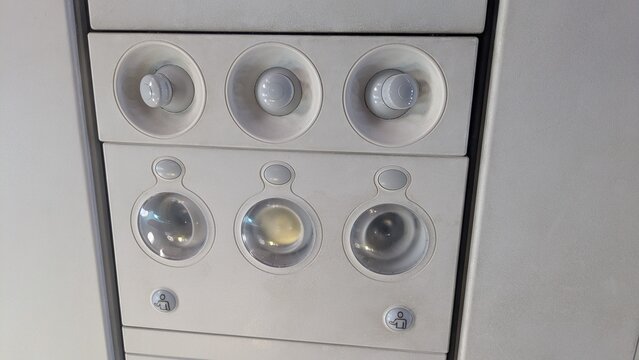 Close-up of aircraft cabin air conditioning and lighting control panel with adjustable vents and illuminated buttons.