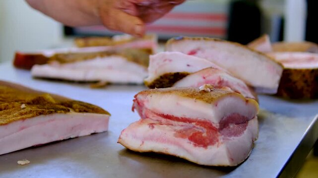 market pork lard. Stack of thick sliced cured pork belly with visible fat layers and rind texture arranged for sale as traditional spanish food product in local market setting