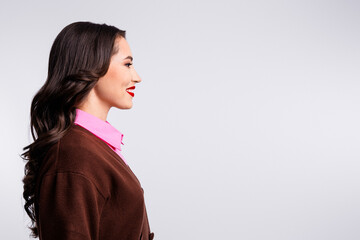 Professional side profile portrait of a cheerful businesswoman with brown hair in stylish attire against white background © deagreez